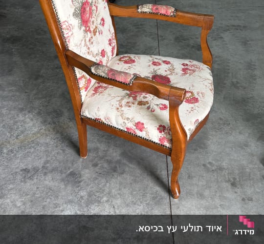 כיסא עץ עם ריפוד פרחוני על רצפת בטון